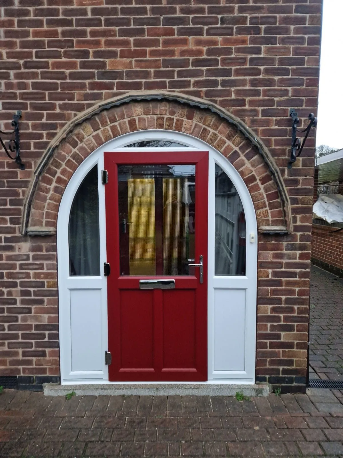 Liniar residential door in red under an arched brick porch