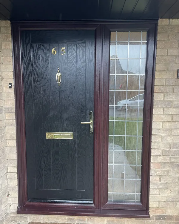 Black woodgrain composite front door with brass numerals, knocker and letterplate, in a rosewood-effect frame with a leaded glass side panel.