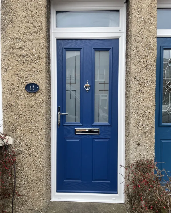 Royal blue composite front door with decorative glass panels and a frosted toplight above, fitted in a pebbledash wall.