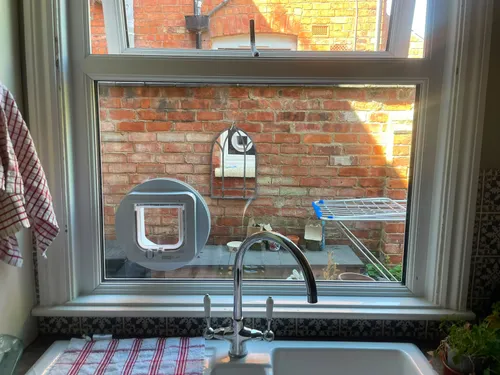 SureFlap microchip cat flap fitted into a kitchen window pane above a Belfast sink