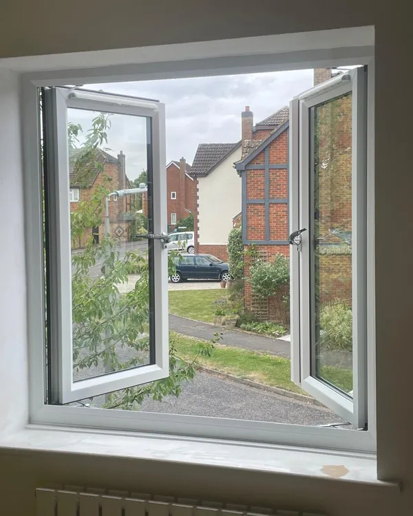 Inside view of a white uPVC window with both casements open, looking out over a residential street.
