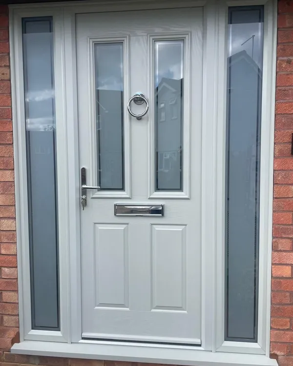 Light grey composite front door with two glazed panels and a chrome ring knocker, flanked by full-height obscure glass side panels.