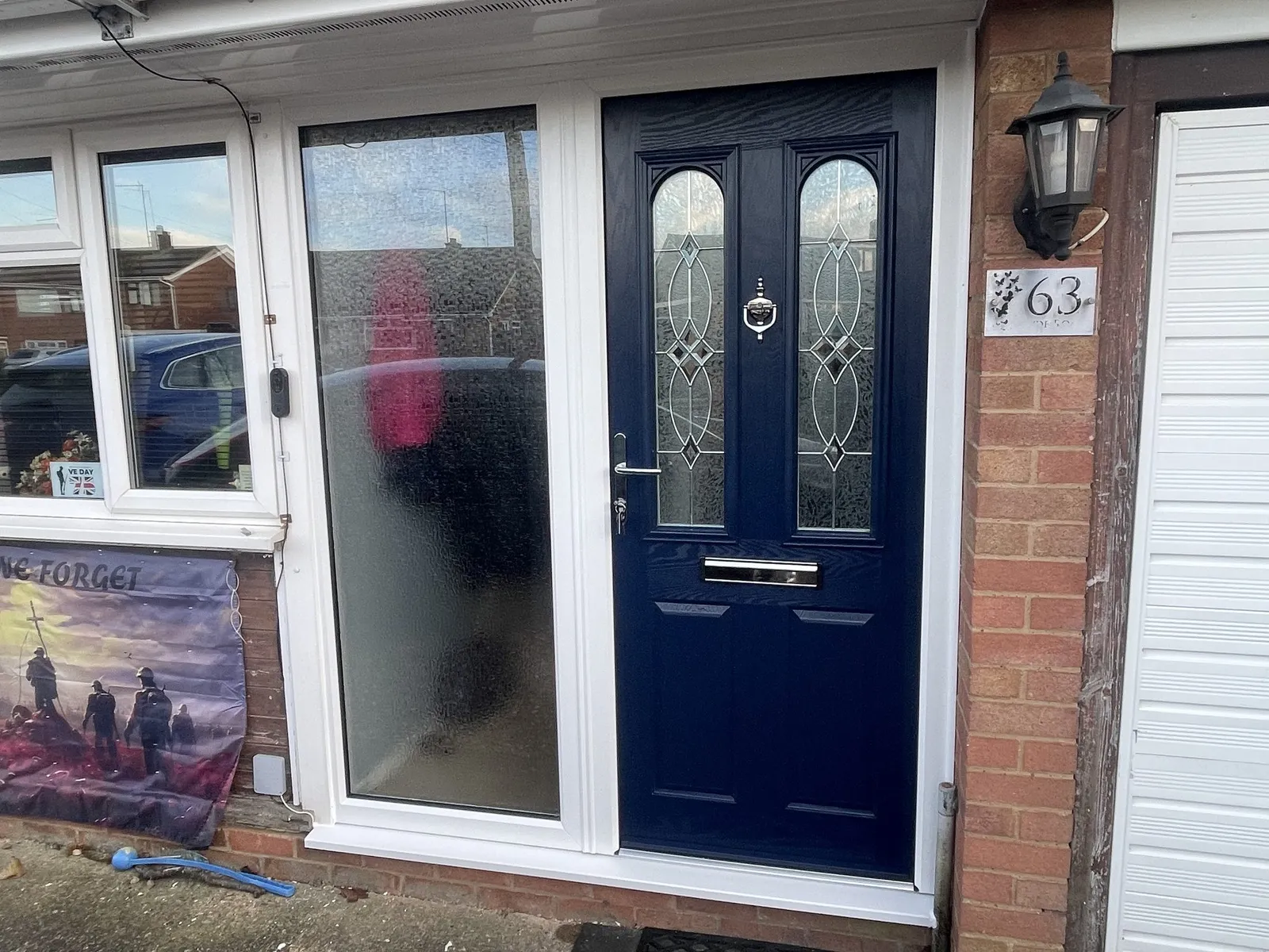 Navy blue composite front door with decorative glass, set in a white uPVC frame with a full-height frosted side panel.