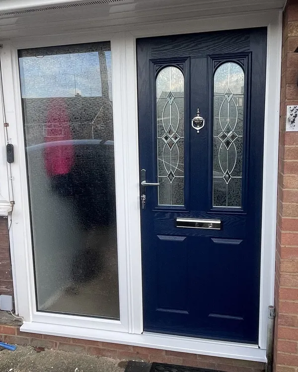 Navy blue composite front door with decorative glass, set in a white uPVC frame with a full-height frosted side panel.