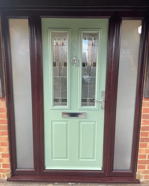 Sage green composite front door with leaded glass panels, in a rosewood-effect frame with frosted side panels.
