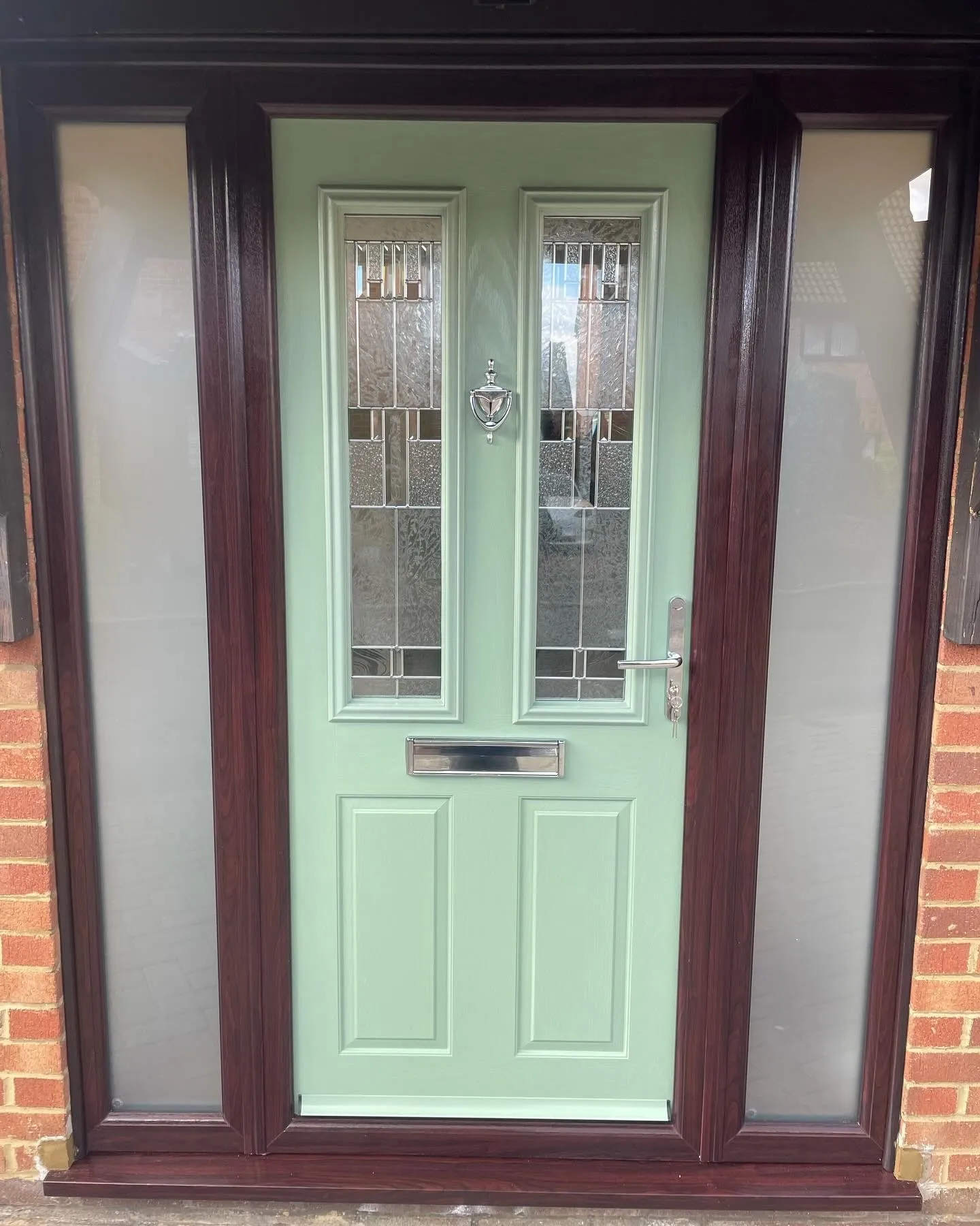 Sage green composite front door with leaded glass panels, in a rosewood-effect frame with frosted side panels.