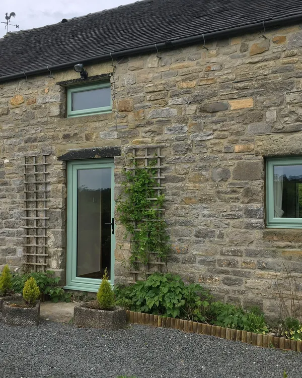 Green UPVC windows and door installed in a traditional stone property