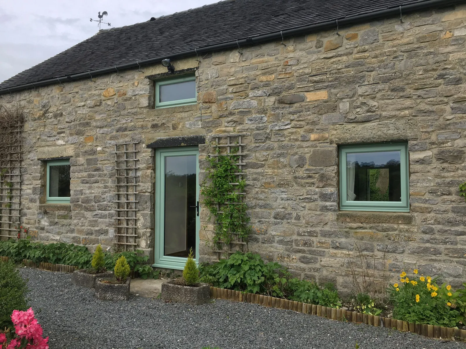 Green UPVC windows and door installed in a traditional stone property