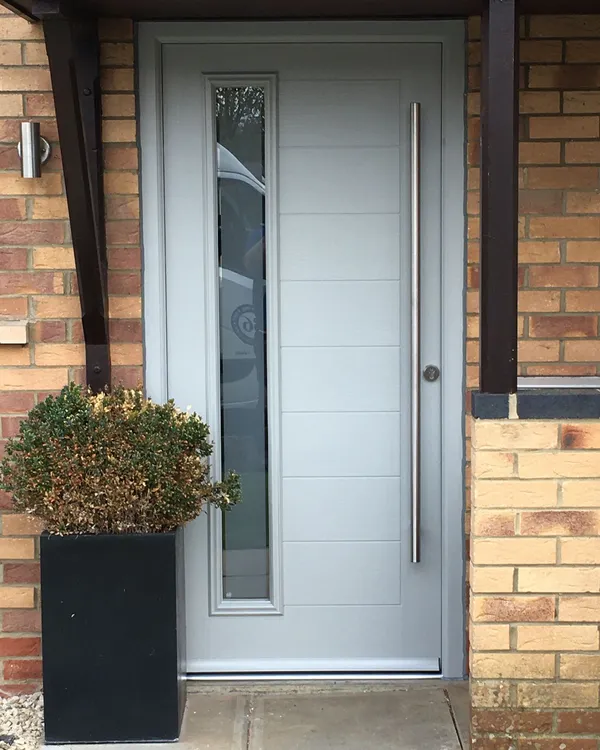 Light grey composite front door with modern handle and glazed side panel