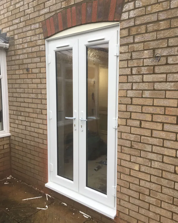 White UPVC French doors installed in a brick property