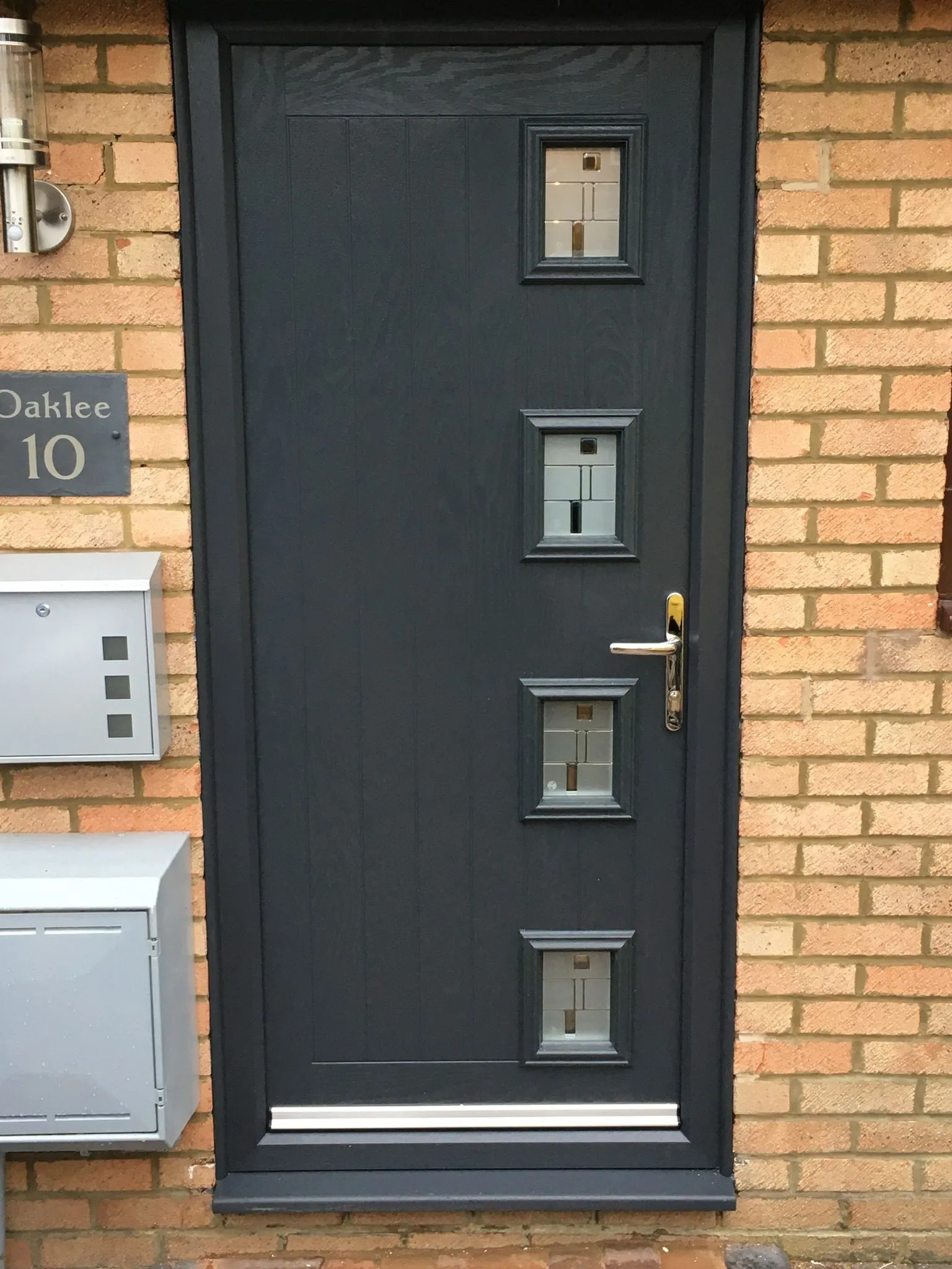 Modern grey composite front door with four decorative glazed panels