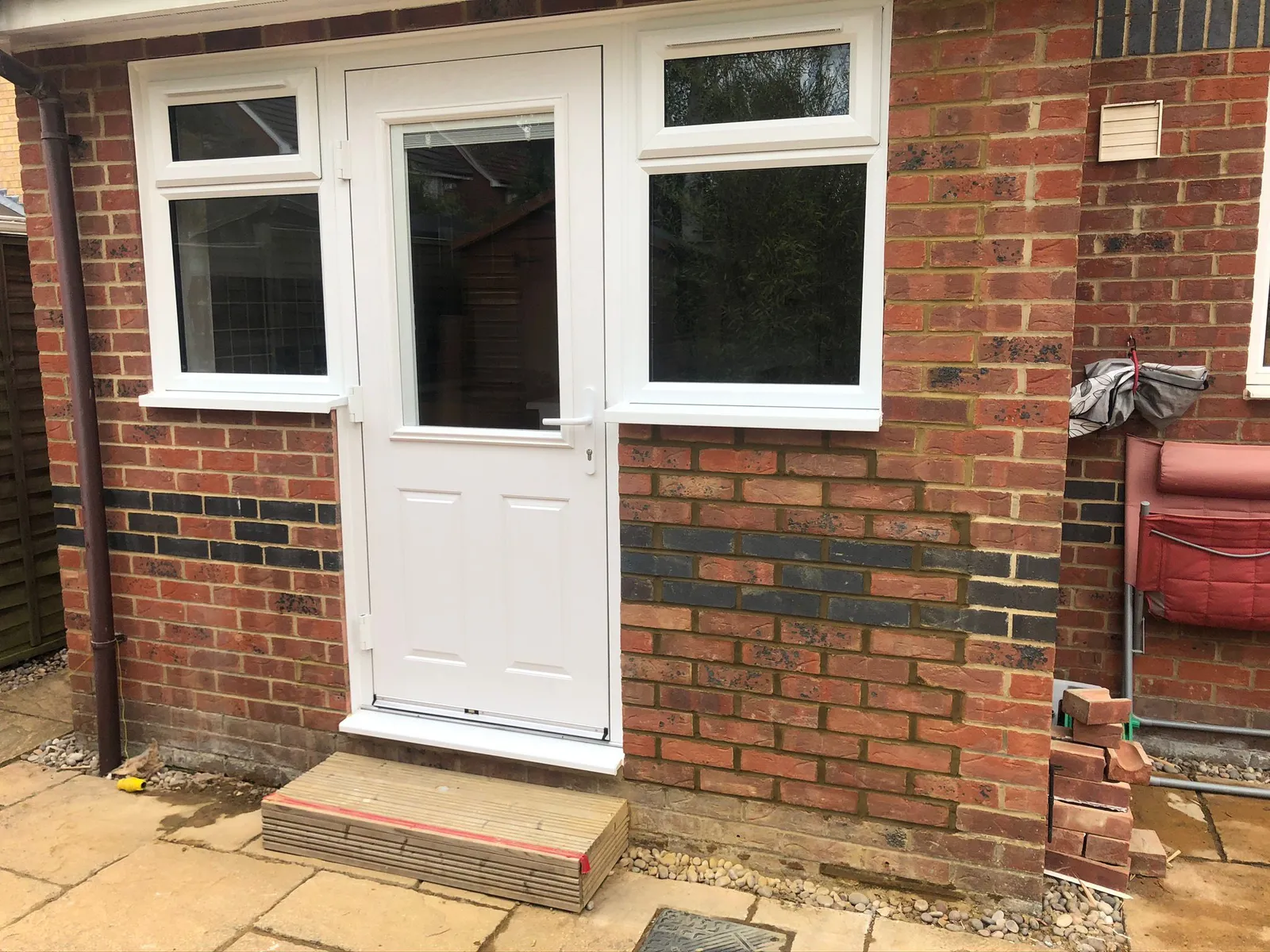 White UPVC back door with side windows installed in brick property