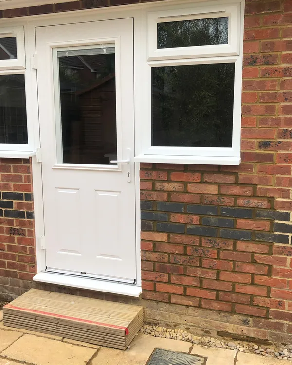 White UPVC back door with side windows installed in brick property