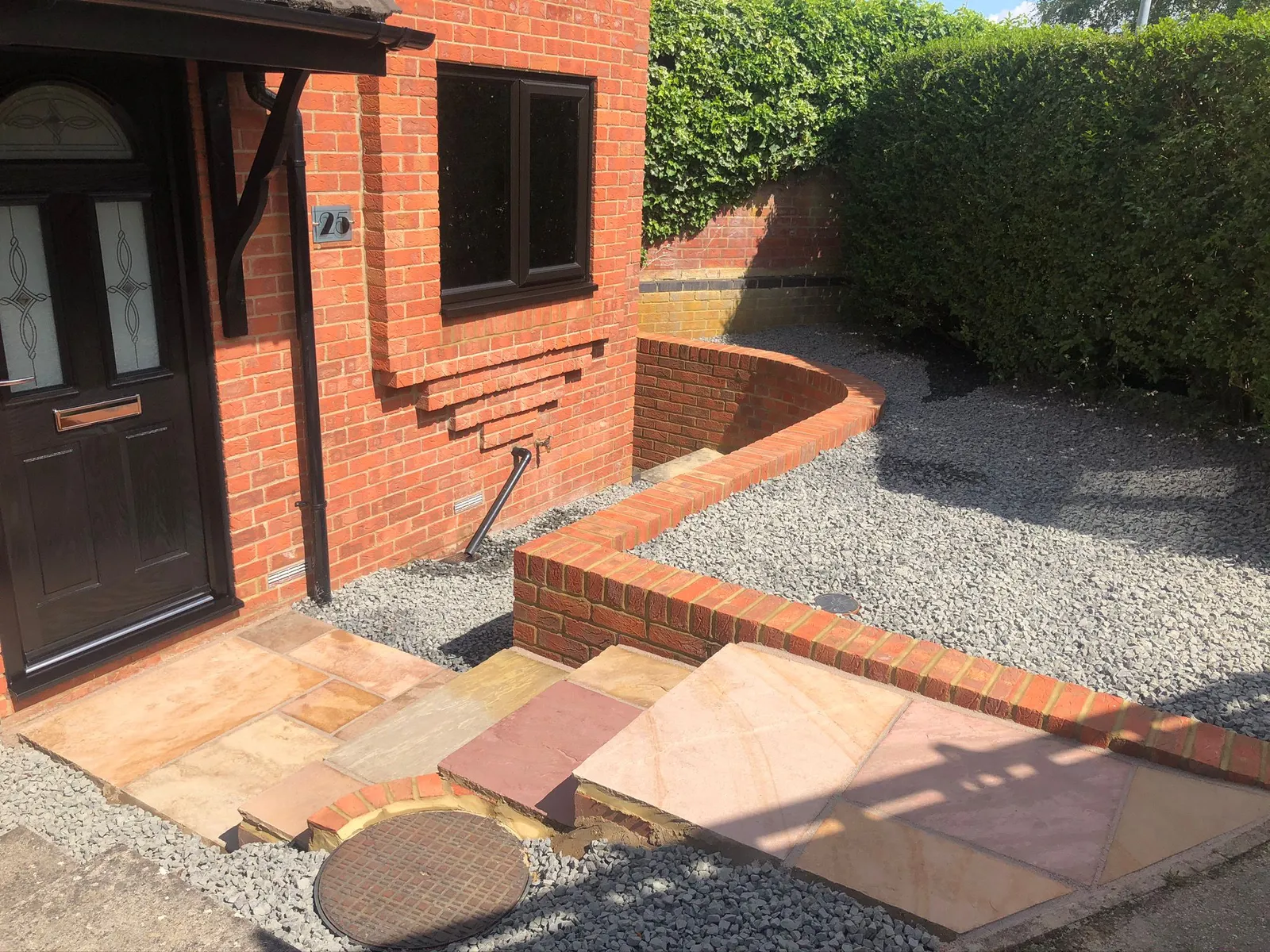 Black composite front door with matching black UPVC windows in a brick property