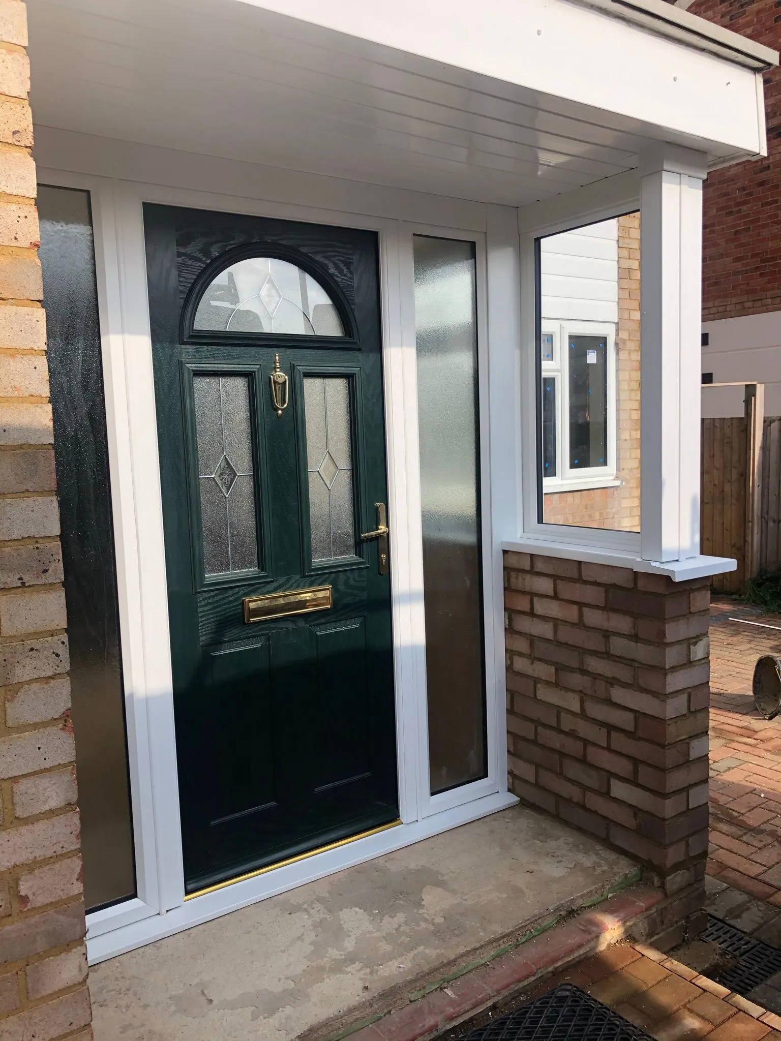 Green composite front door with decorative glazed panels and side windows