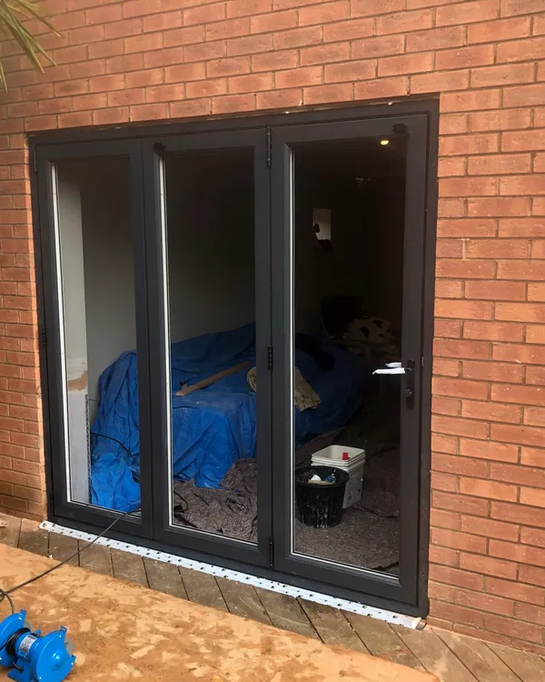 Modern anthracite grey bi-fold doors installed in a brick home