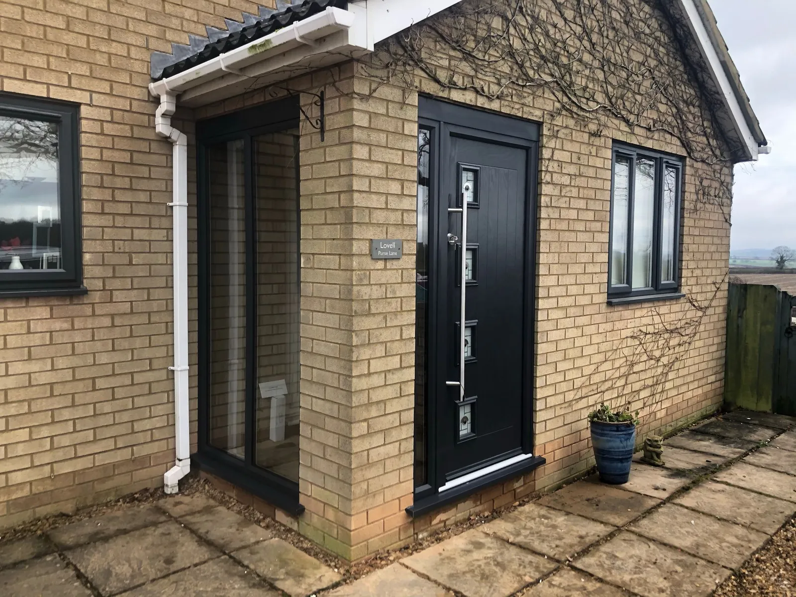 Black composite front door with vertical decorative glazing and chrome handle