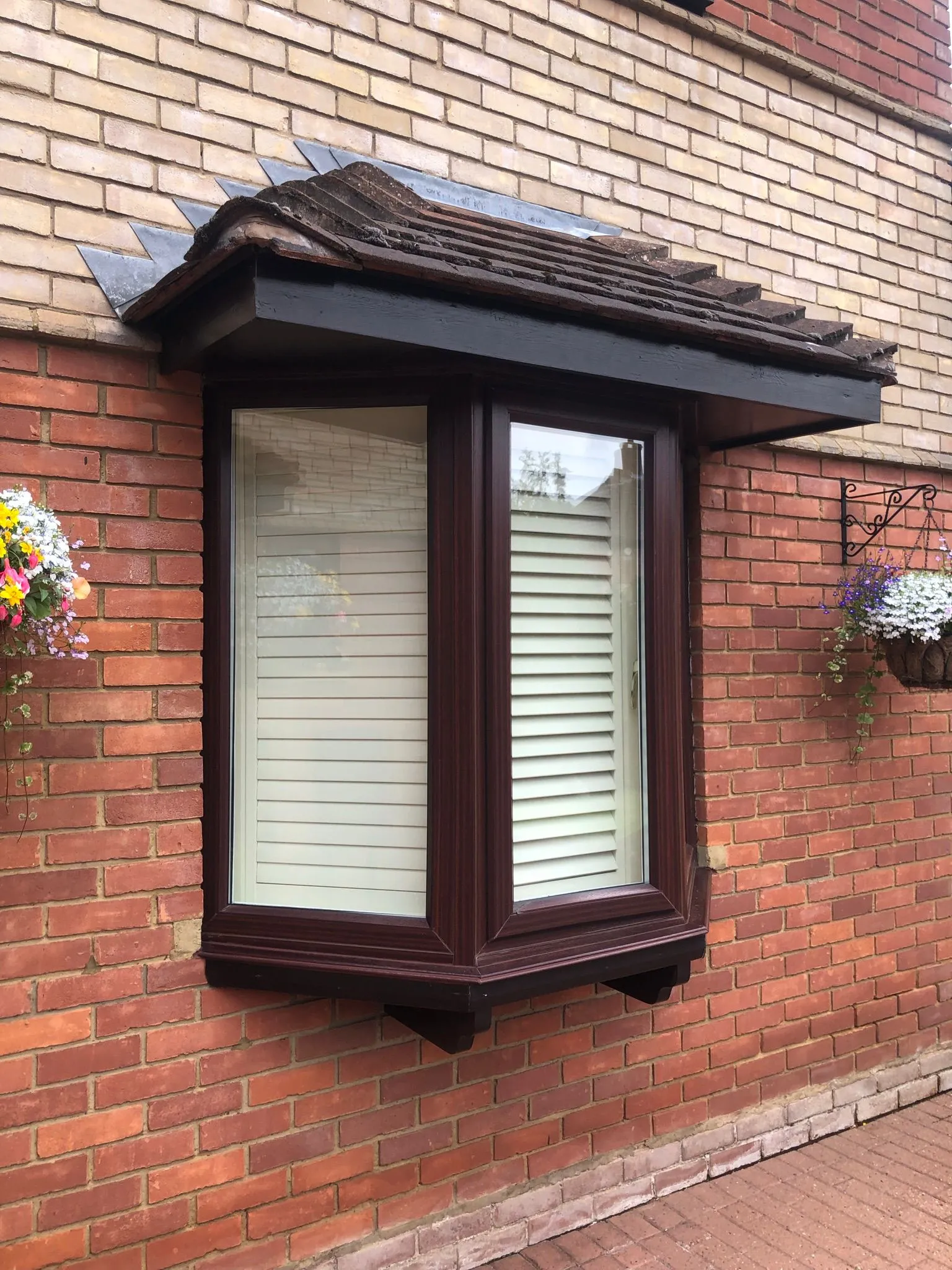 Brown UPVC bay window with tiled canopy roof on a brick property