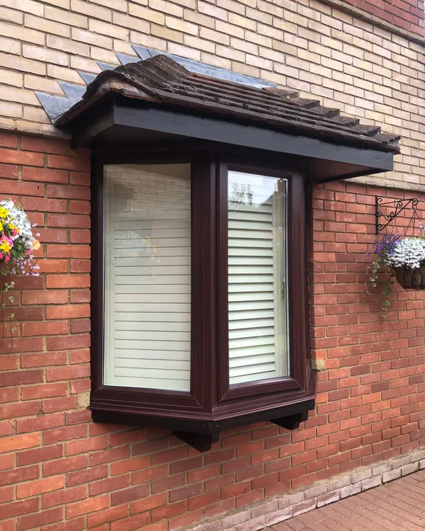 Brown UPVC bay window with tiled canopy roof on a brick property