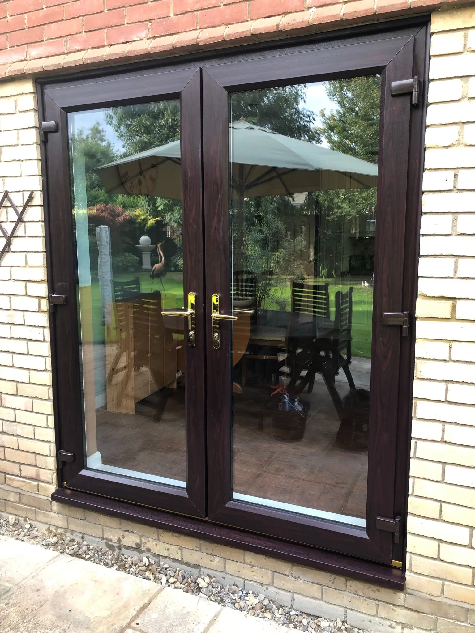 Dark woodgrain UPVC French doors opening to garden