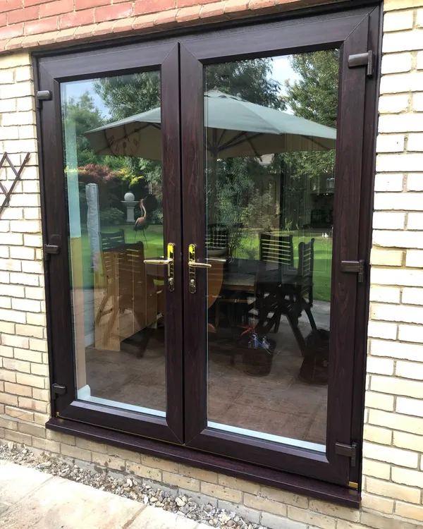 Dark woodgrain UPVC French doors opening to garden