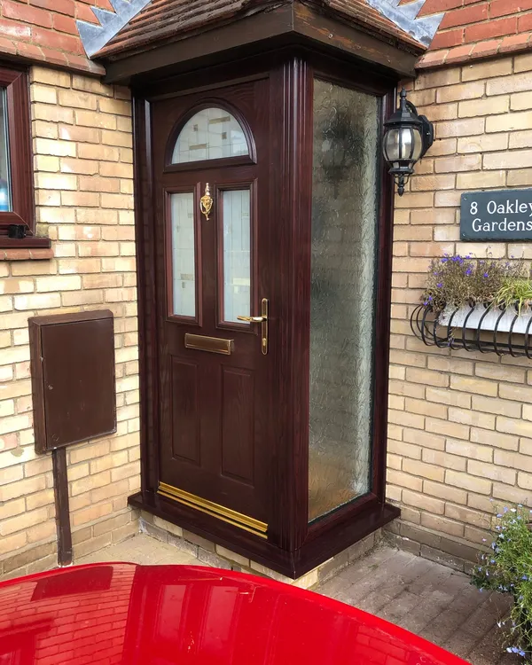 Dark woodgrain composite front door with frosted side panel and porch canopy