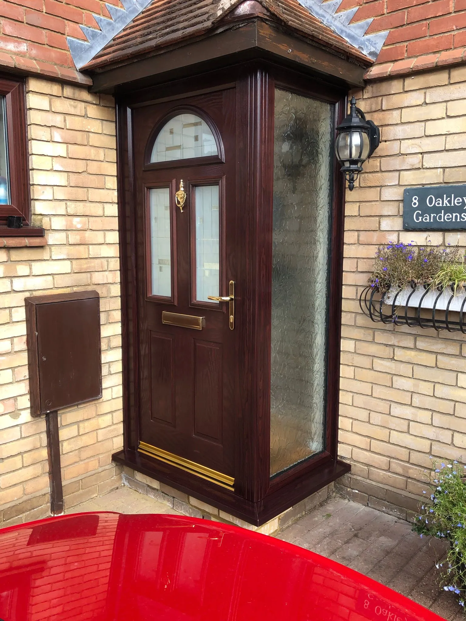Dark woodgrain composite front door with frosted side panel and porch canopy