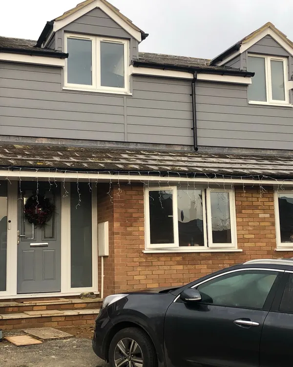 Grey composite door with frosted side panels and new UPVC windows on extended house