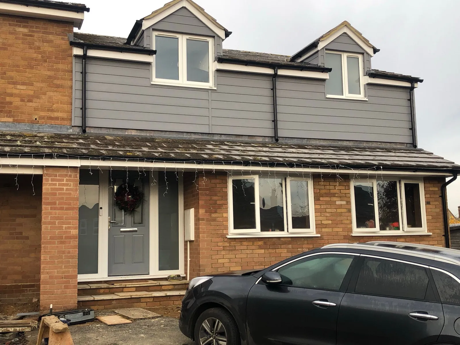 Grey composite door with frosted side panels and new UPVC windows on extended house