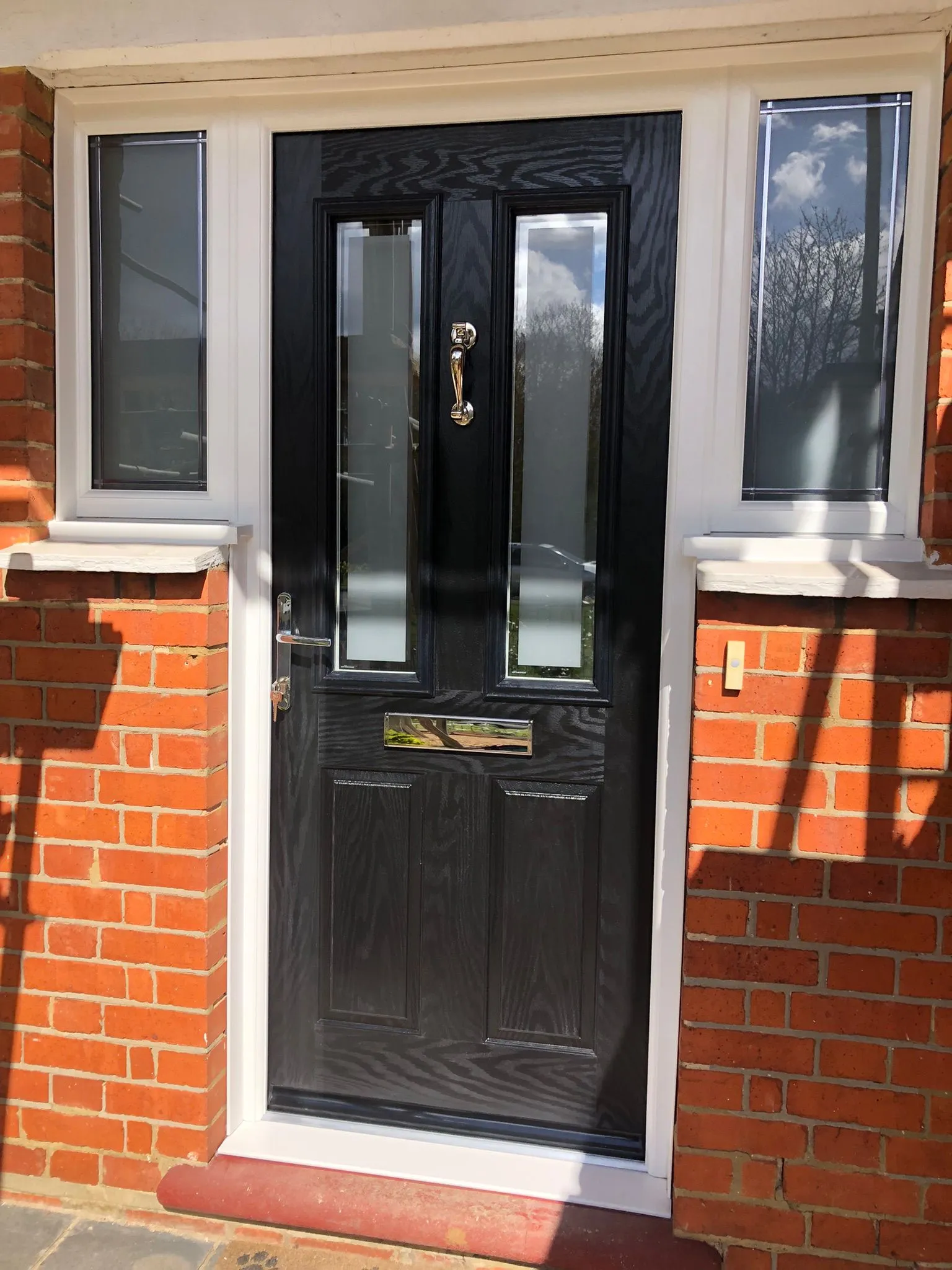 Black composite front door with two vertical glazed panels and chrome furniture