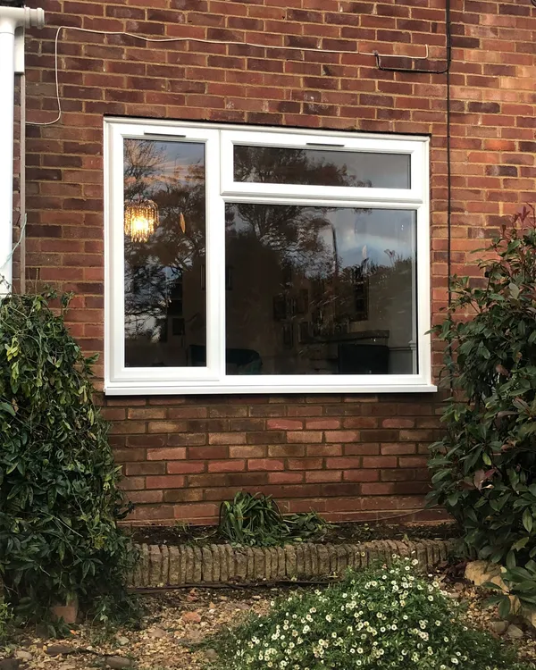 White uPVC casement window with top opening vent fitted in a red brick wall.