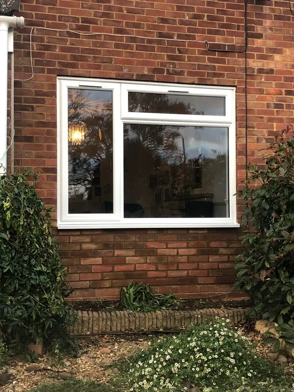 White uPVC casement window with top opener installed in red brick wall.