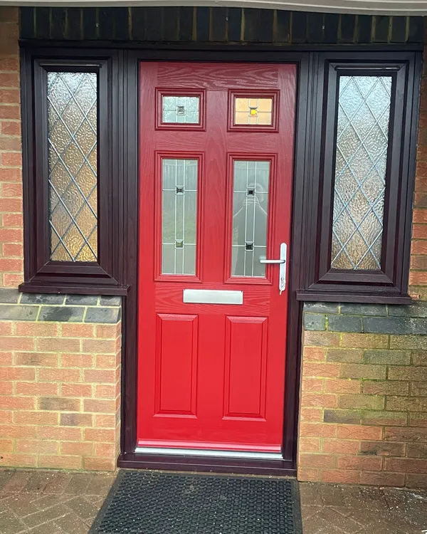Red composite entrance door with decorative glass and matching side panels.