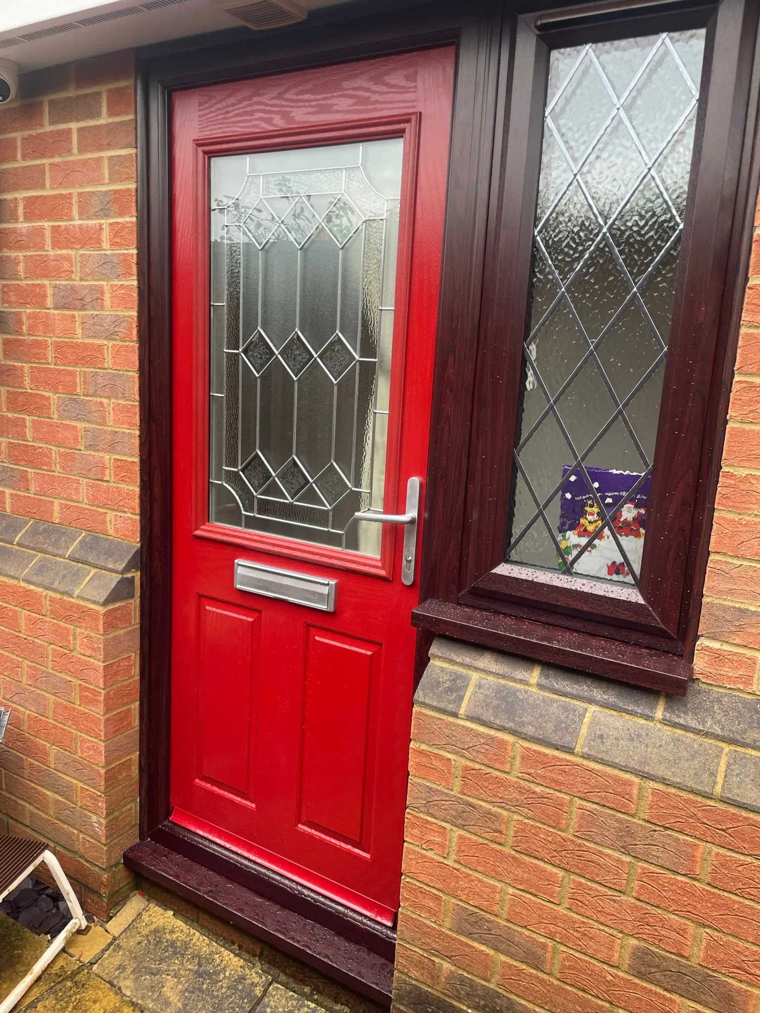 Red composite back door with patterned glazed panel and white uPVC frame.