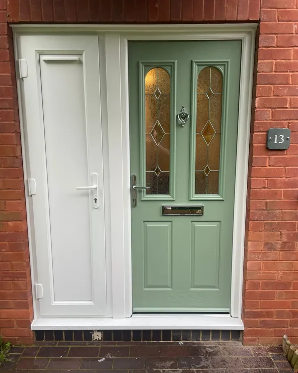 Pale green composite entrance door with side panel and decorative glass inserts.
