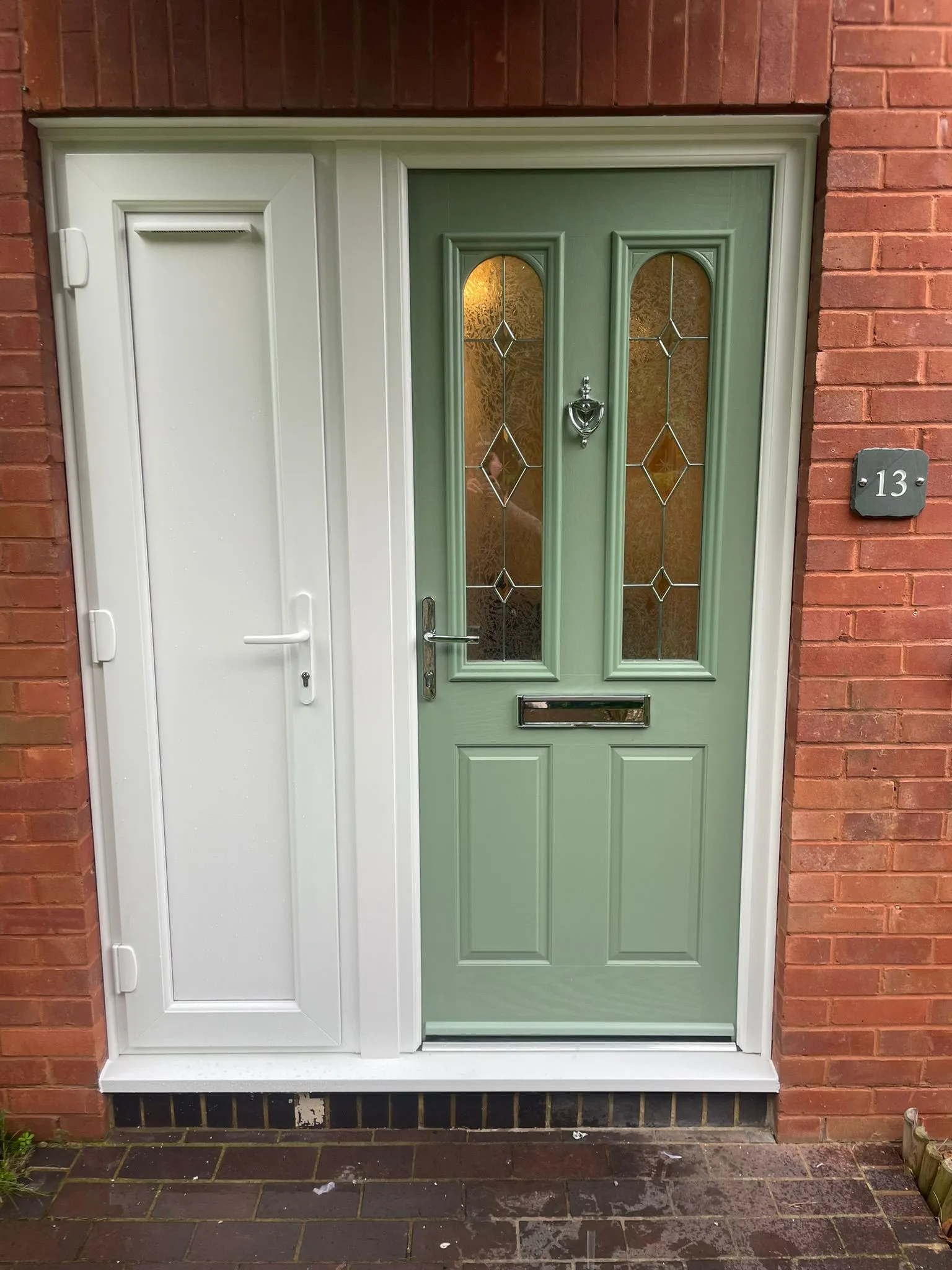 Pale green composite entrance door with side panel and decorative glass inserts.