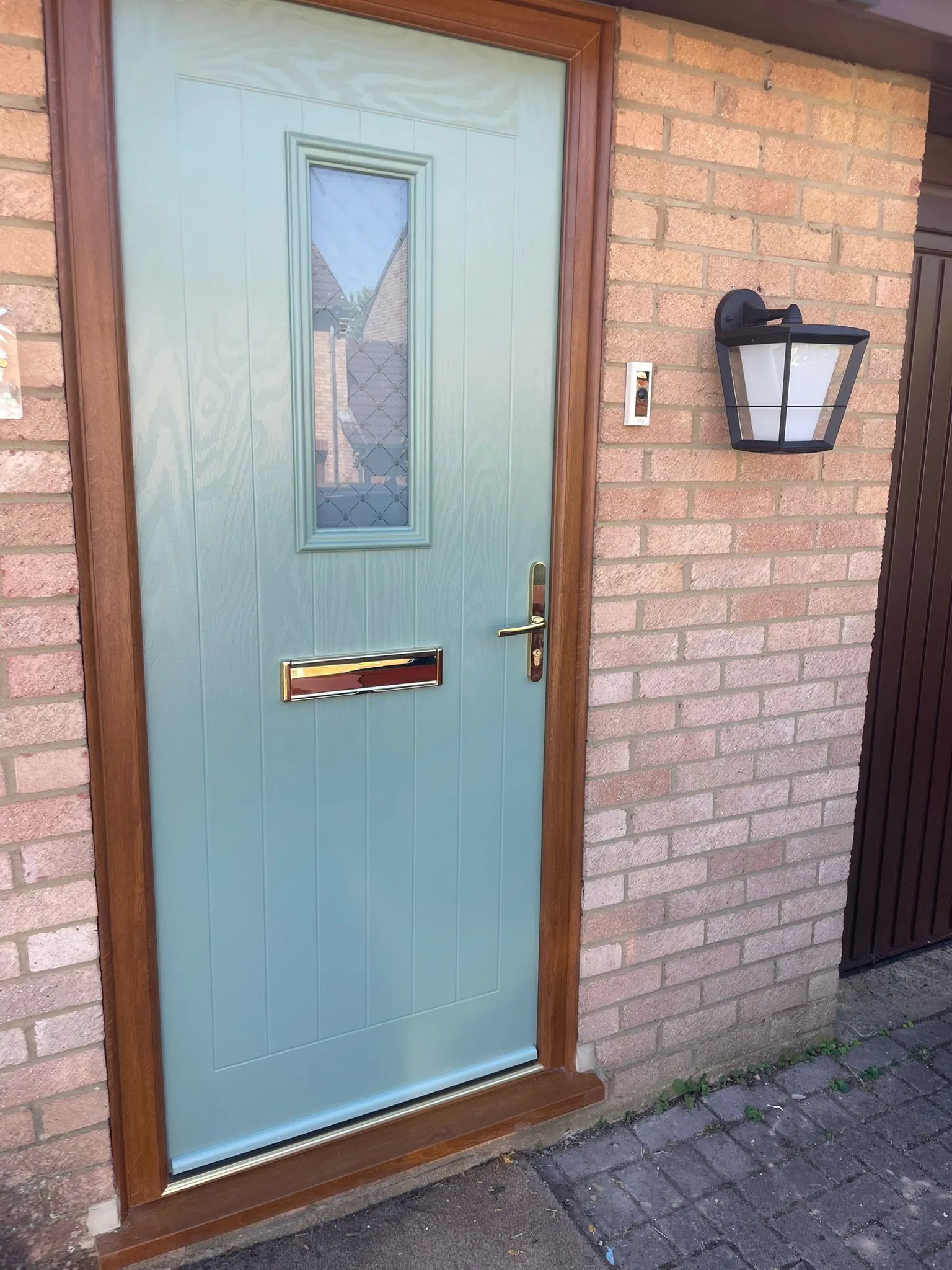 Light blue composite entrance door with square glazed panel and timber effect frame.