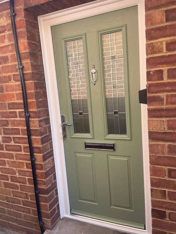 Sage green composite front door with decorative glass panels and chrome knocker.