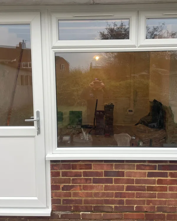 White uPVC back door with glazed panel and large fixed casement window next to it.
