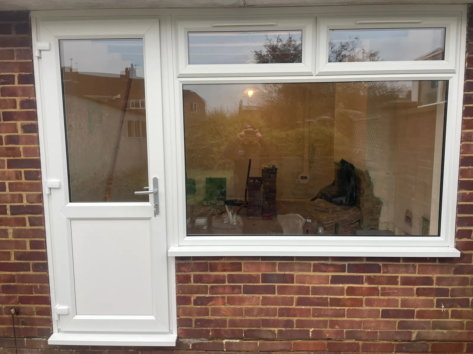 White uPVC back door with glazed panel and large fixed casement window next to it.