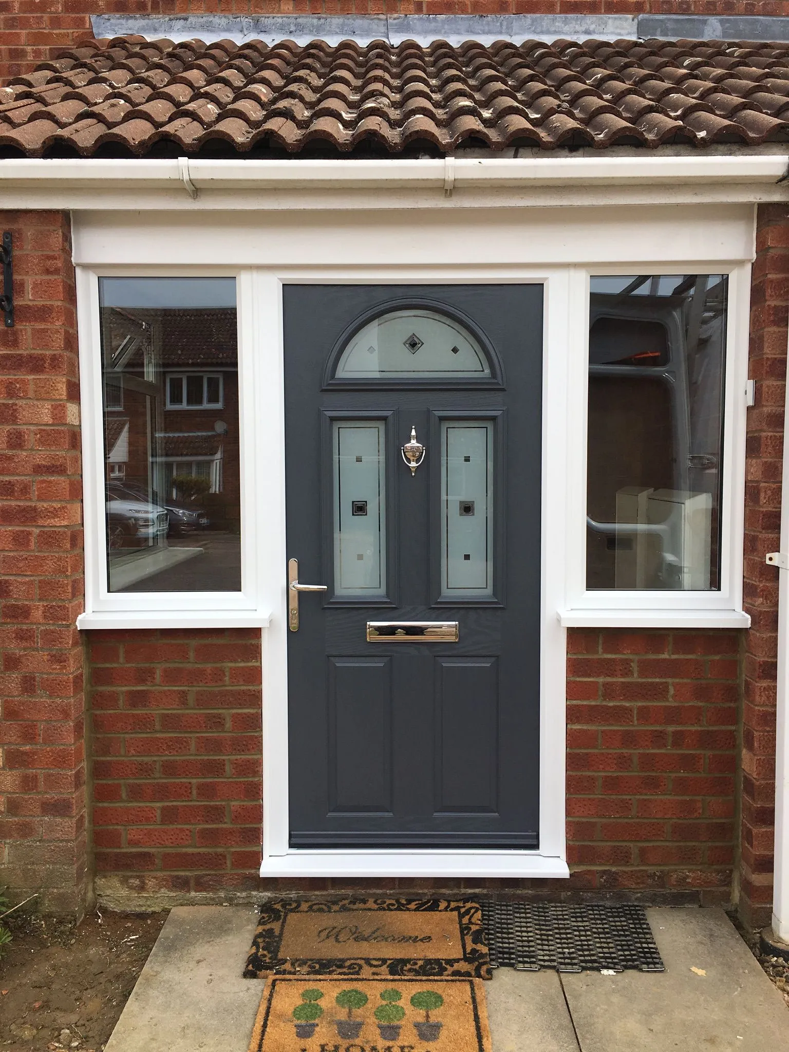 Grey composite front door with decorative glazed panels and UPVC surround