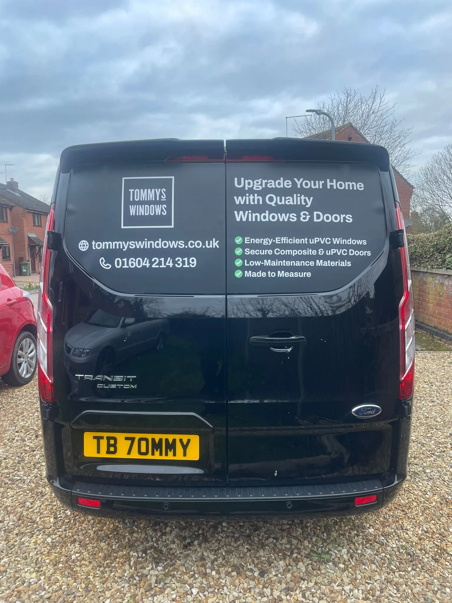 The Tommy's Windows van, a black Ford Transit Custom with the company logo and phone number on the back doors
