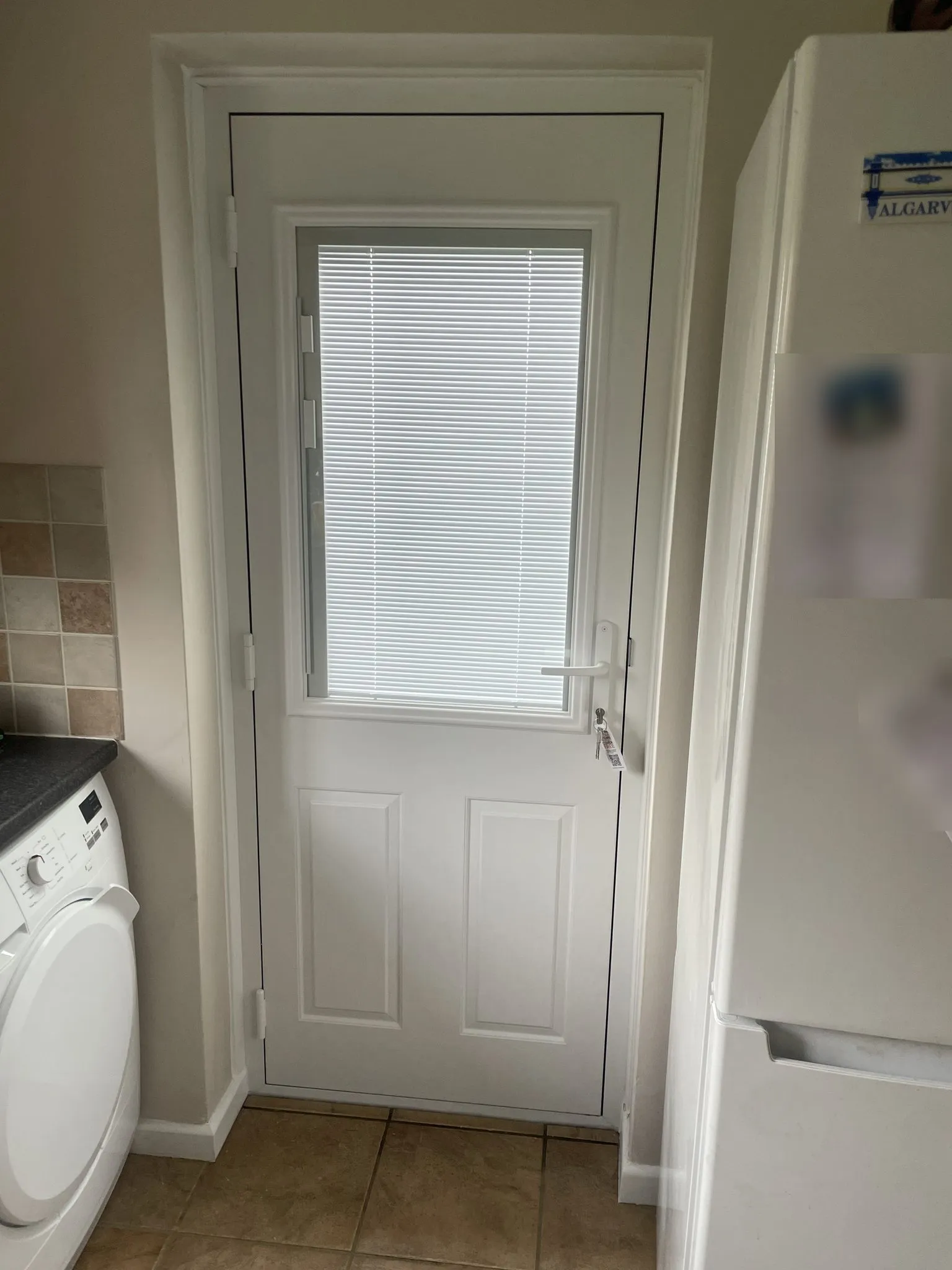 Inside view of a white composite back door with integral blinds sealed within the glass, in a utility room.