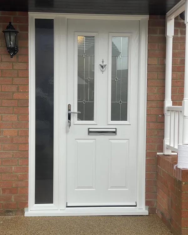 White composite front door with two leaded glass panels and chrome furniture, beside a tall side panel with dark obscure glass.