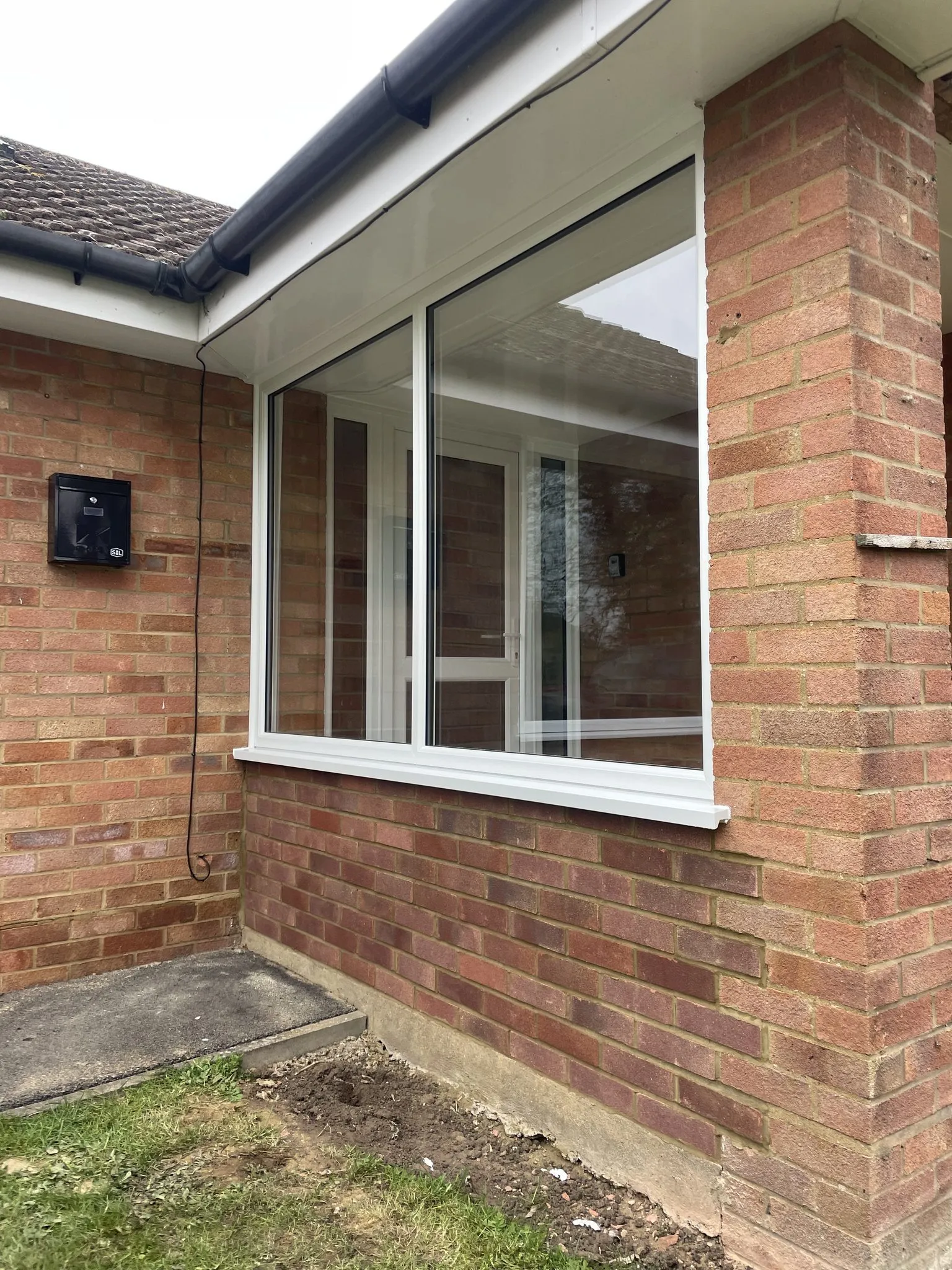 White uPVC windows meeting at the corner of a red brick bungalow.