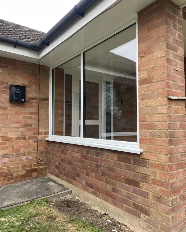 White uPVC windows meeting at the corner of a red brick bungalow.
