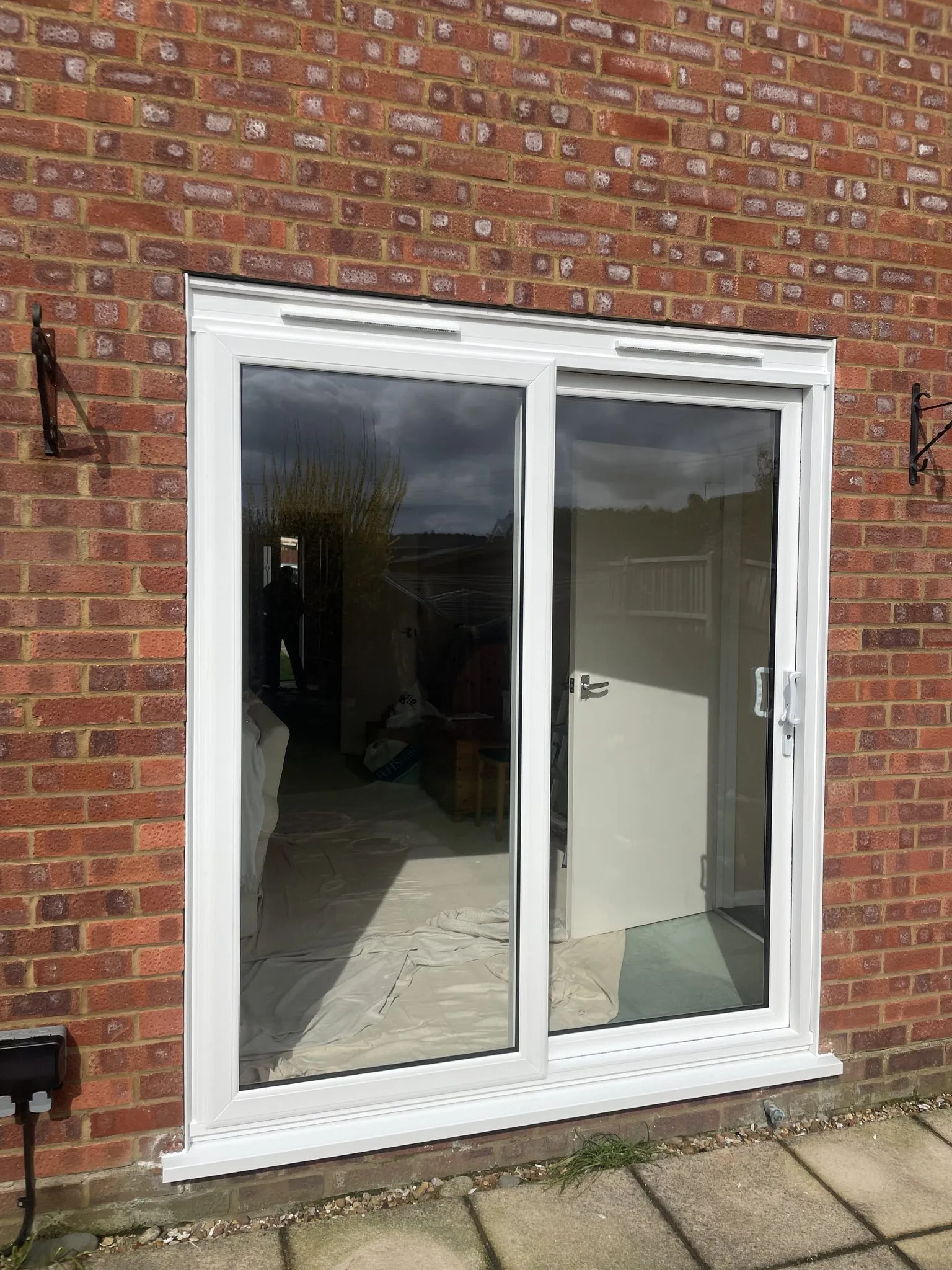 Two-pane white uPVC sliding patio door installed in a red brick wall.