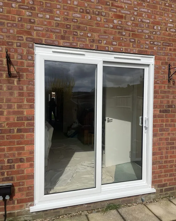 Two-pane white uPVC sliding patio door installed in a red brick wall.