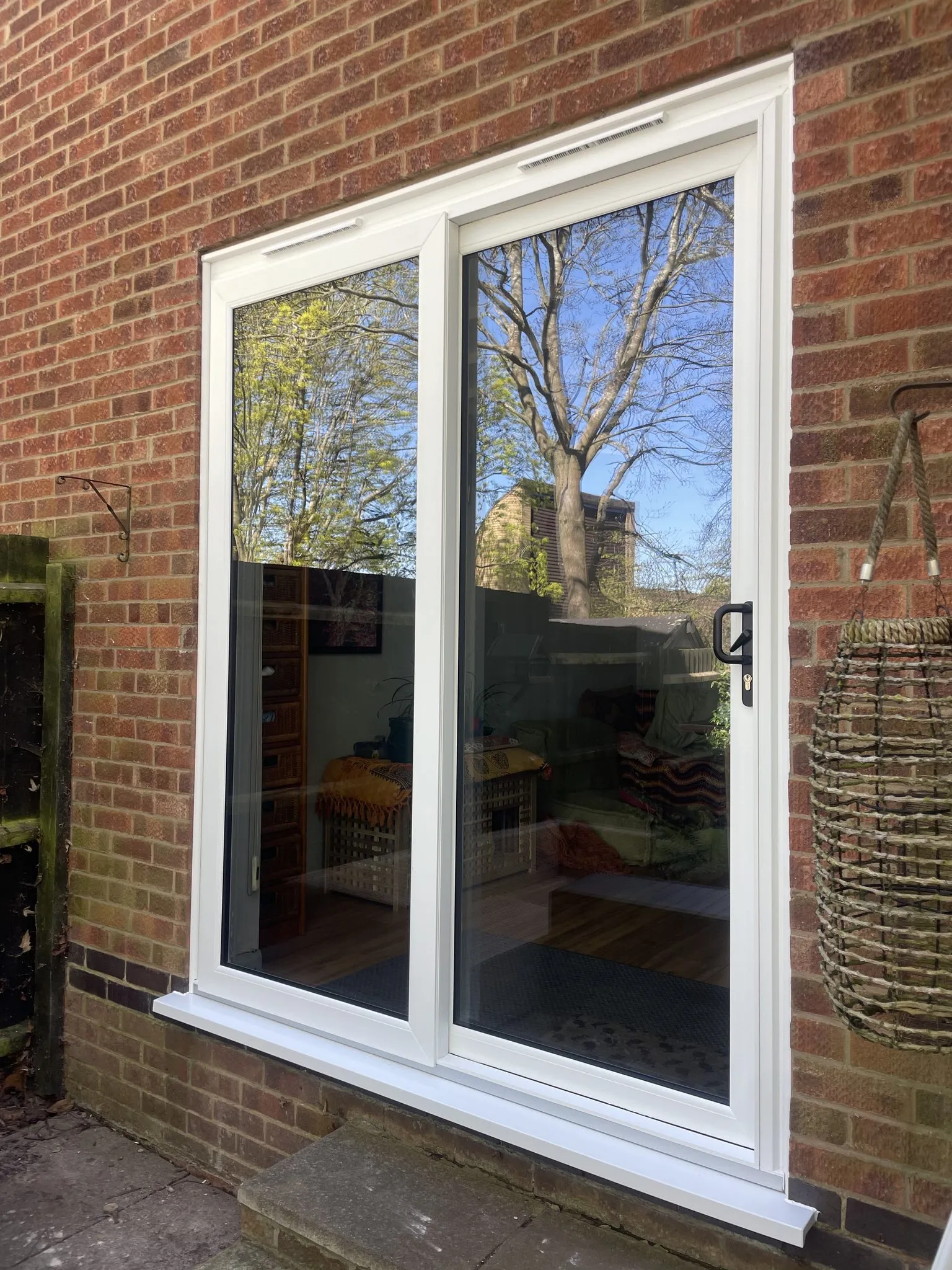 Large two-pane white uPVC sliding patio door fitted in a red brick wall.
