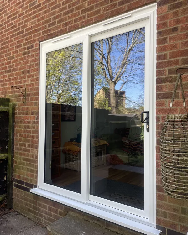 Large two-pane white uPVC sliding patio door fitted in a red brick wall.